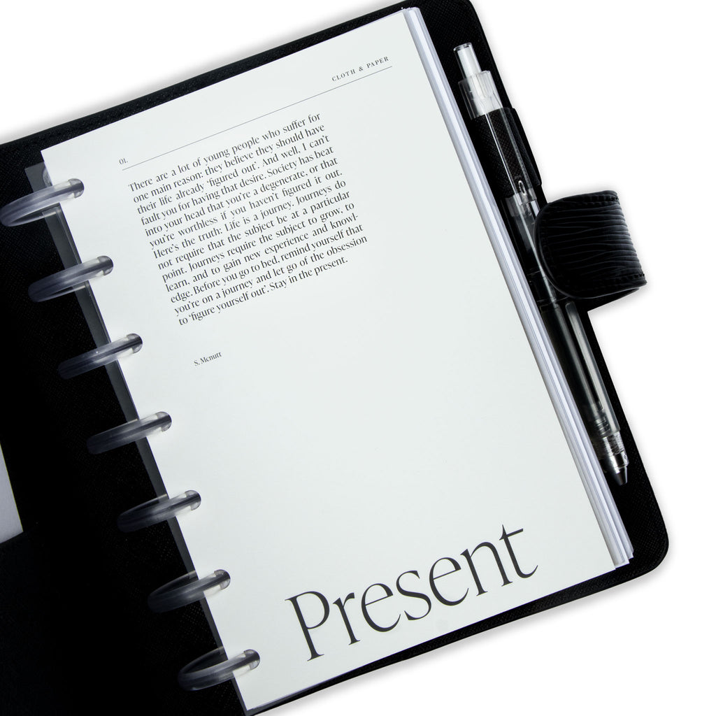 Front of the first dashboard styled inside of a discbound planner. The planner has clear discs and is tucked into a black leather cover. The leather cover has a clear pen in the pen loop.