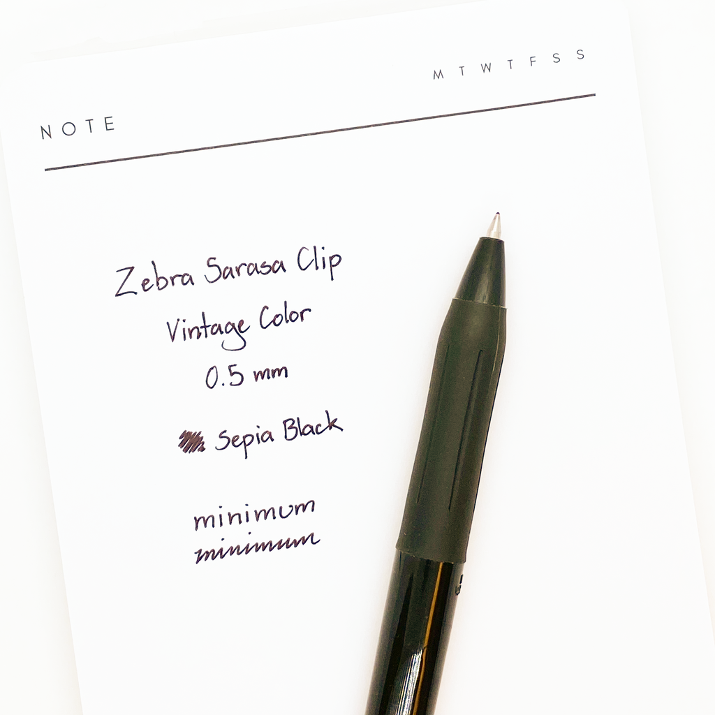Zebra Sarasa Clip Vintage Color, Cassis Black, Cloth and Paper. Pen resting on paper displaying writing sample.