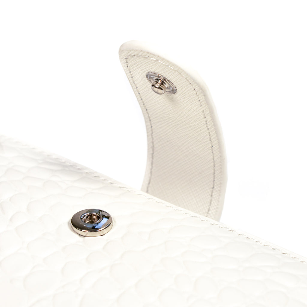 Close up on the snap closure detail on a white agenda with silver snap hardware.