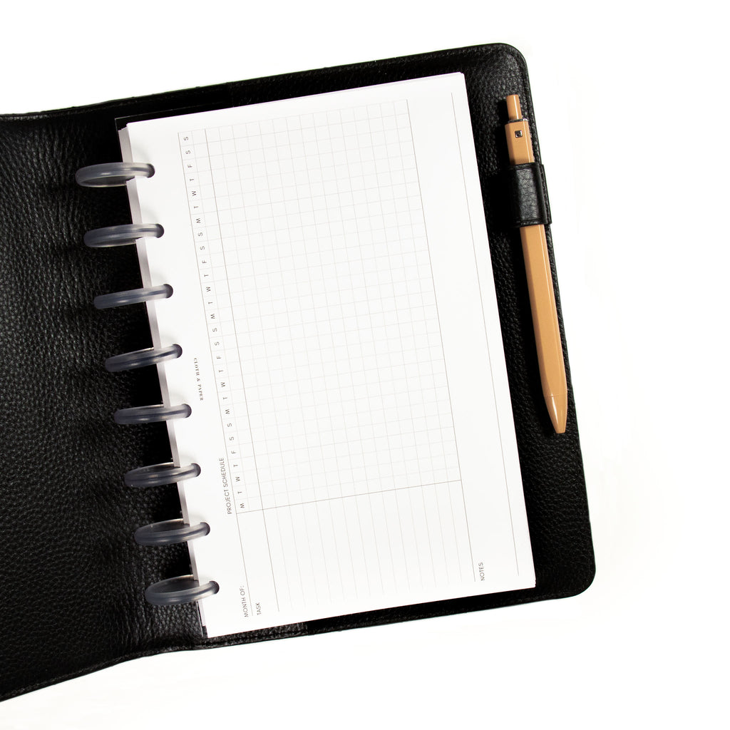 Gantt Chart Planner Inserts, Refreshed Layout displayed inside a discbound planner and Leather Agenda Cover. There is a Cinnamon Dolce Gel Pen in the agenda's pen loop.