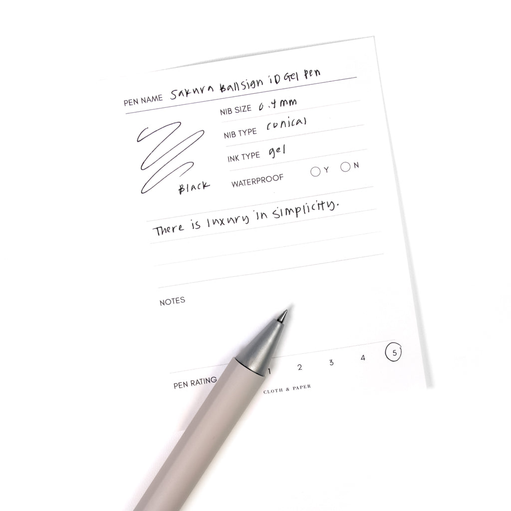 Sakura Ballsign iD Gel Pen, 0.4 mm, Cloth and Paper. Black pen resting on pen test sheet displaying writing sample.