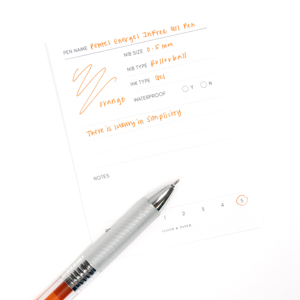 Pentel Energel Infree Gel Pen, Orange, Cloth and Paper. Close up on pen nib resting on pen test sheet.