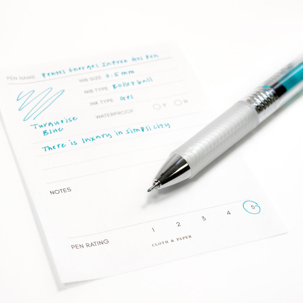Pentel Energel Infree Gel Pen, Turquoise-Blue, Cloth and Paper. Pen resting on pen test sheet displaying writing sample.