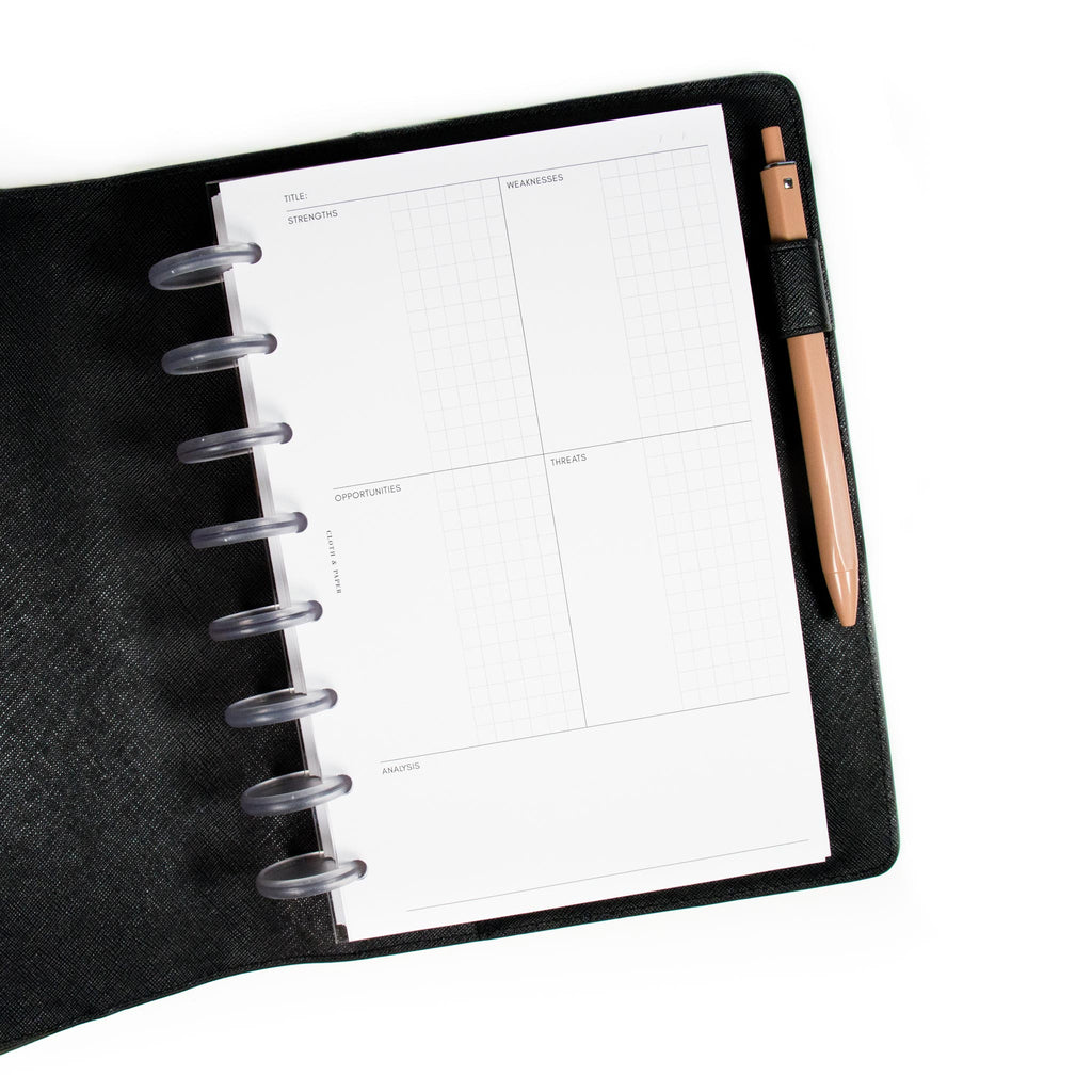 SWOT Analysis Planner Inserts in the Refreshed Layout styled inside a discbound planner. The planner is in a black leather planner cover with a pen tucked into the pen loop.
