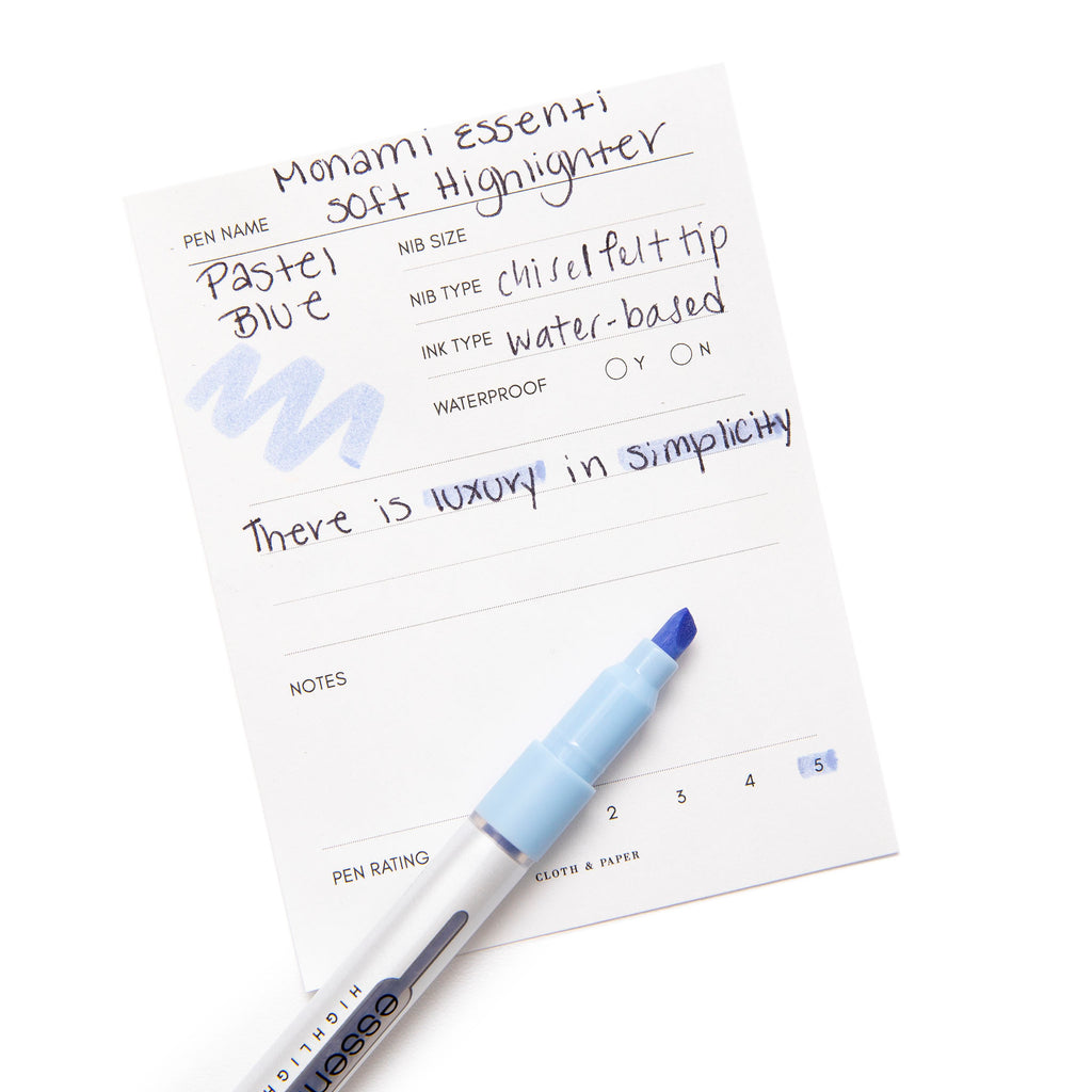 Monami Essenti Soft Highlighter, Pastel Blue, Cloth & Paper. Highlighter resting on pen test sheet displaying writing sample.