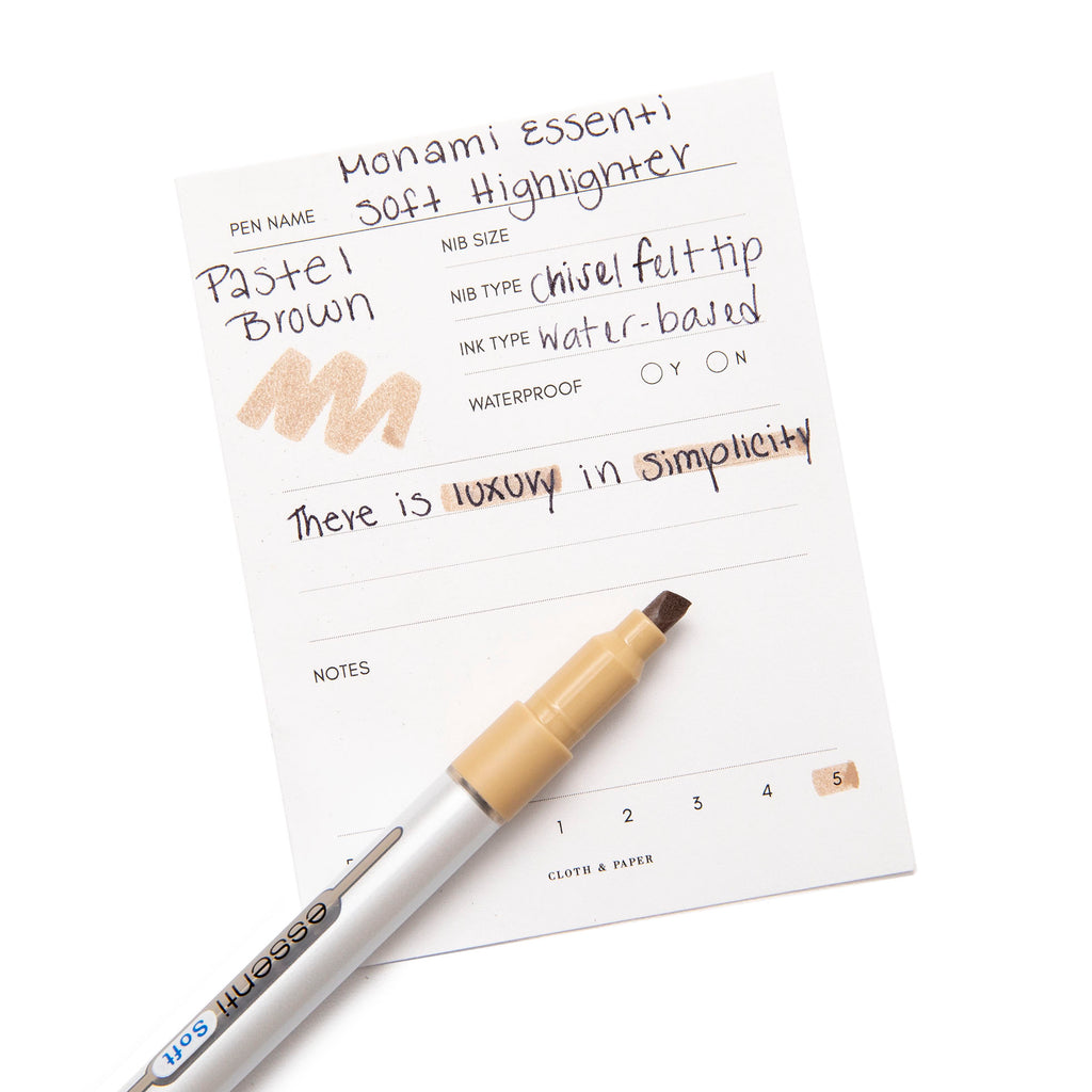 Monami Essenti Soft Highlighter, Pastel Brown, Cloth and Paper. Highlighter resting on pen test sheet displaying writing sample.