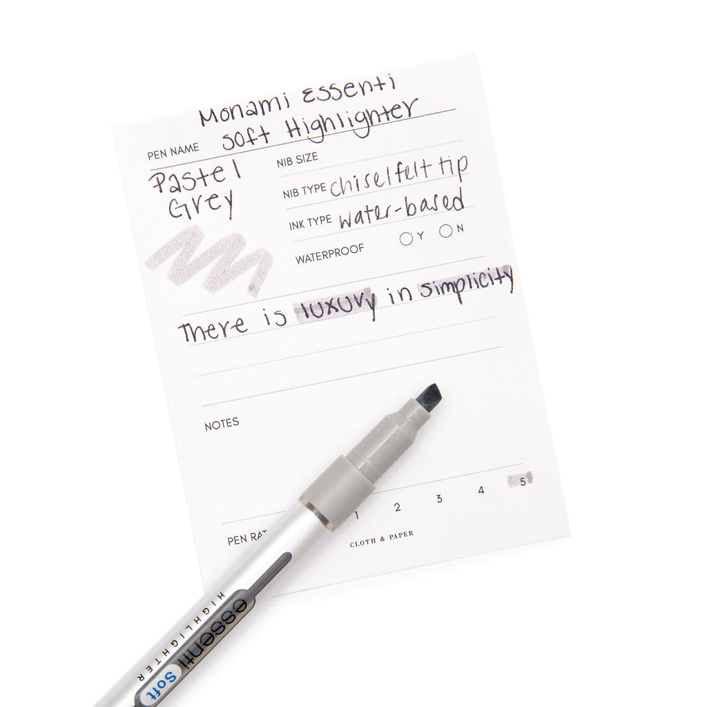 Monami Essenti Soft Highlighter | Pastel Grey | Cloth and Paper. Highlighter resting on pen test sheet displaying writing sample.