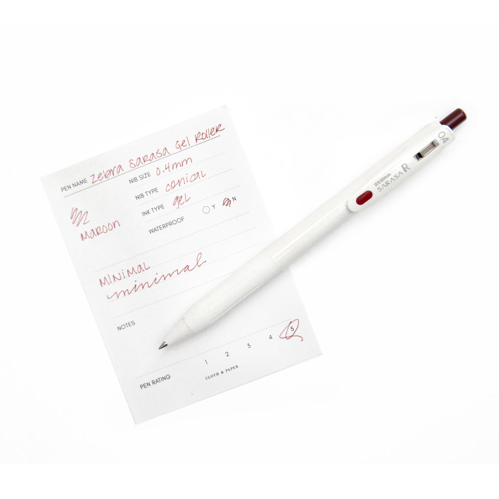 Zebra Sarasa R Pen, 0.4 mm, Red Black, Cloth and Paper. Pen resting on pen test sheet displaying writing sample.